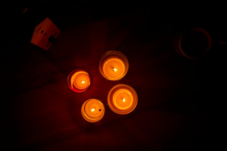 Red candle burning in dark with focus on single candle in foreground. Candlelight in dark...