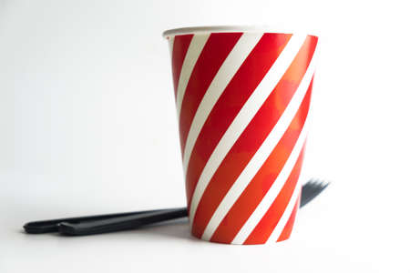Paper cup with plastic spoon and fork on table prepared for party.