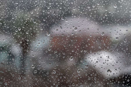 Rain drops on window glass surface with cloudy background . Natural Pattern of raindrops isolated on...