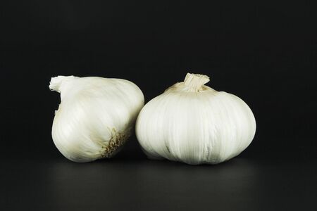Garlic bulbs, isolated on a textured black background.の写真素材