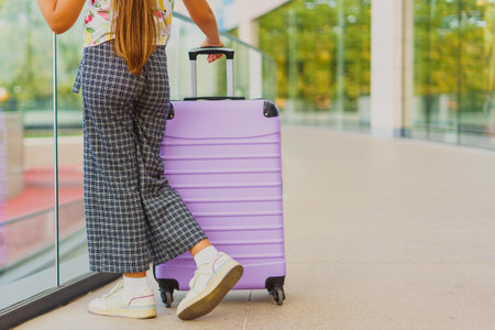 One purple large suitcase stands outside against the backdrop of the terminal and green nature. Vacation and travel concept.の写真素材