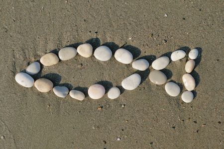 Christian symbol made of stones on sand - fish shapeの写真素材