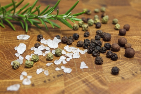 Salt, pepper and rosemary on a chopping boardの写真素材