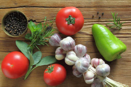 Tomatoes, garlic and fresh herbs on wooden background.の写真素材
