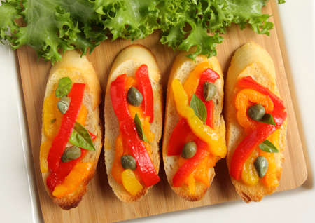 Crostini, small toasts with colored peppers and spices on a wooden board.の写真素材