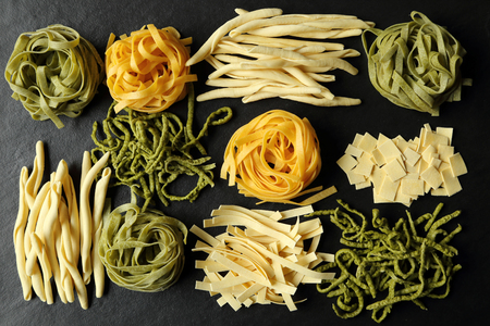 Various types of pasta on a black ceramic background.の写真素材