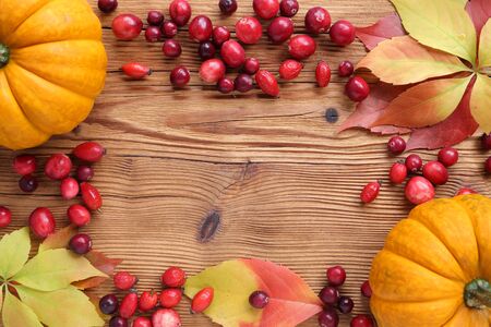 Frame with red cranberries and autumn leaves  on wooden background.の写真素材