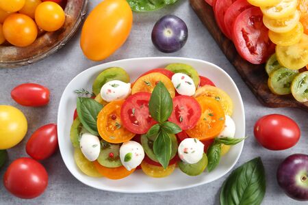 Tomato salad and colorful tomatoes sliced on a wooden chopping board.の写真素材