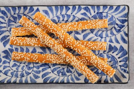 Bread sticks with salt and sesame seeds top view on a blue background.
