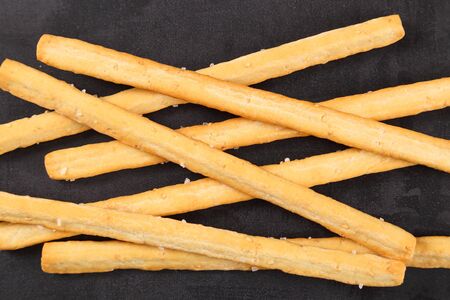 Bread sticks with salt  top view on a black background.