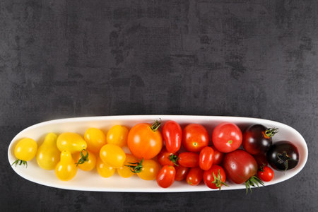 Colorful tomatoes on a plate  on a black background.の写真素材