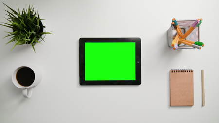 A mans finger touching an tablet computer with a green screen. A tablet is on the white table. View from the top. Close-up.の写真素材