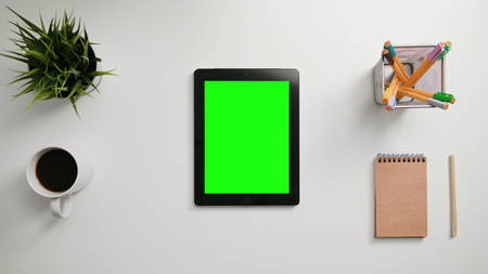 A mans finger scrolling on the green touchscreen. A tablet is on the white table. View from the top. Close-up.の写真素材