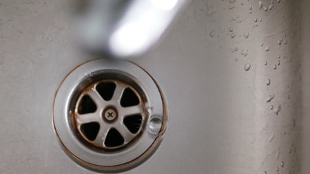 Water dripping from a tap into a sink. Slow motion. View from the top. Soft focus. Close-up shotの写真素材