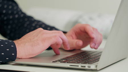 Mans hands typing on a laptop. Close-up Dolly shot. Soft focus.の写真素材