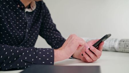 A young man using a smartphone indoors. Close-up Dolly shot. Soft focus.