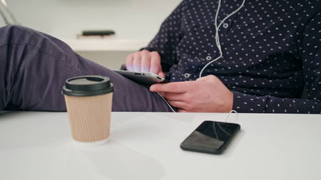 A young man using a tablet indoors. Close-up shot. Soft focus.の写真素材