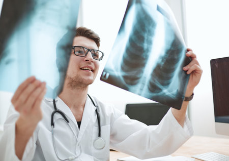 Male doctor radiologist examines x-rays in a medical office.の写真素材
