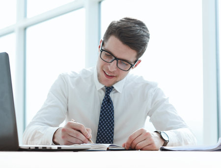 Closeup of business man writing form on clipboard at officeの写真素材