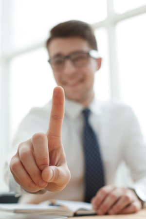Young businessman man showing number one with fingers on handの写真素材