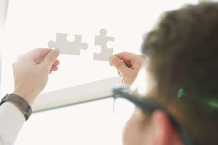 Businessman hands connecting puzzle pieces representing the merging of two companies or joint...