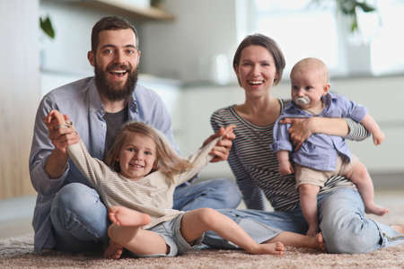 Young parents playing with children in the kitchen