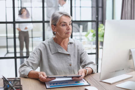 Smiling businesswoman with digital tablet listening during meeting in officeの写真素材