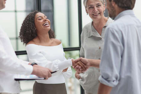 Smiling multiethnic businesspeople shaking hand in officeの写真素材