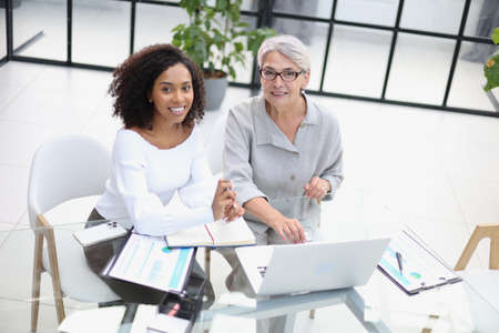 Female colleagues met in the office hall discussing work issues