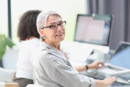 Smiling 60-year-old business woman using a computer at officeの写真素材