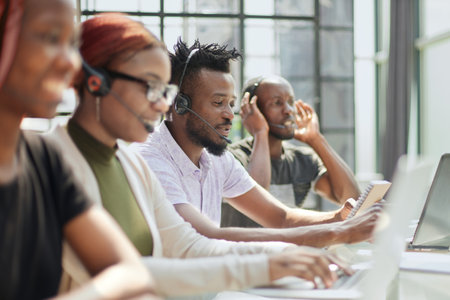 Smiling beautiful African American woman working in call center with diverse teamの写真素材