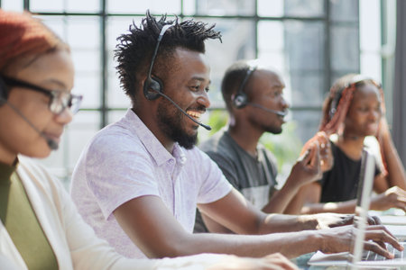 Smiling beautiful African American woman working in call center with diverse teamの写真素材