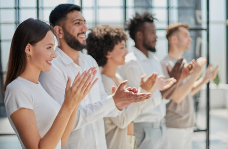 Group of businesspeople sitting in a line and applauding.の写真素材
