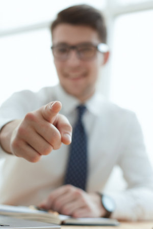 Handsome smiling businessman pointing his finger to youの写真素材