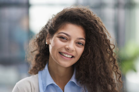 Cheerful girl standing at modern office looking at camera