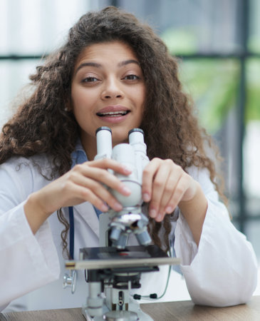Attractive female scientist looking through a microscope