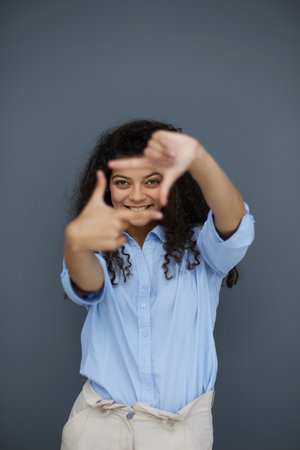 Smiling attractive young business woman in blue shirt posing on gray background