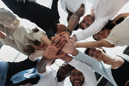 multinational business team looking down putting hands together