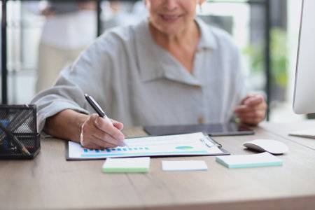 The older stylish woman takes notes in a documentの写真素材
