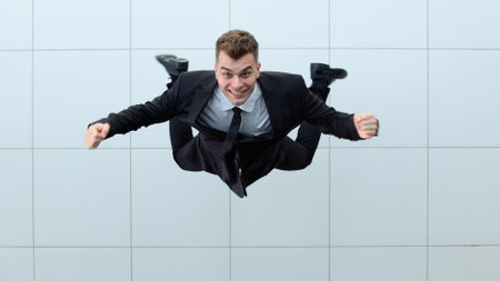 Celebrating success. Low angle view of excited young businessman keeping arms
