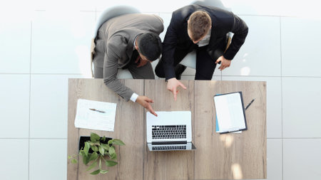 Two successful smiling businessmen are working on a laptop. view from above