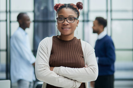 Smiling young woman standing with her arms crossed and looking at camera.の写真素材