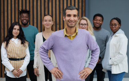 gorgeous casual man in purple shirt standing with hands on hip looking forward happilyの写真素材