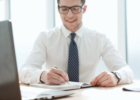 Closeup of business man writing form on clipboard at officeの写真素材