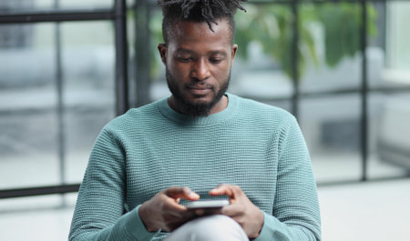 Black man looking at smartphone browsing internet, office technology and digital communicationの写真素材