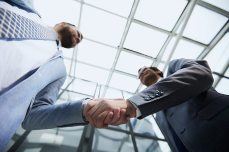 Delighted businessmen shaking hands, greeting acquaintance in the office,の写真素材