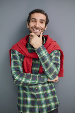 Smiling young unshaven business man posing against gray wall background studio portrait.の写真素材