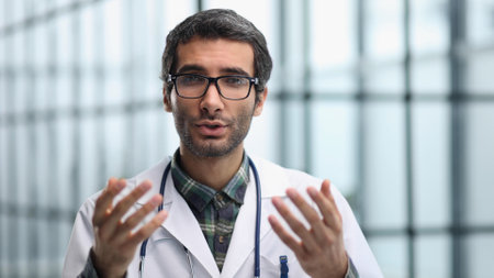 Head shot portrait male doctor talking online with patient, making video call, looking at camera