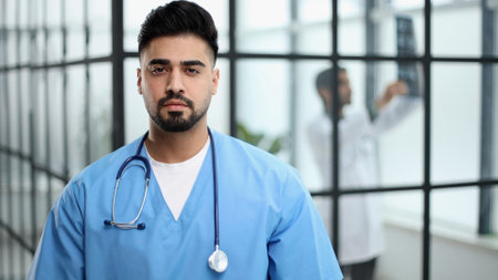 Portrait of confident male doctor standing in hospital lobbyの写真素材