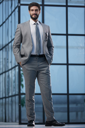 The brains behind the business. Portrait of a confident young businessman standing with his arms crossed in front in an office.の写真素材